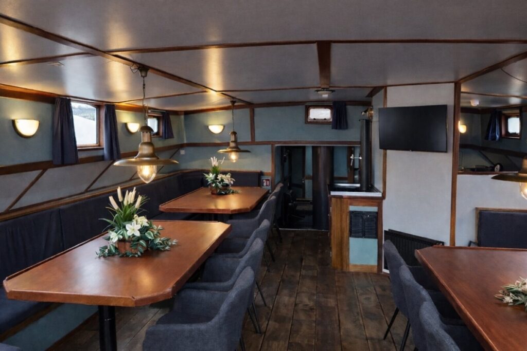 Sfeervol interieur van een zeilschip met zitruimte en keuken voor overnachten aan boord in Kampen